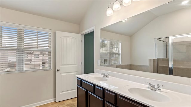 full bath featuring double vanity, a tile shower, vaulted ceiling, and a sink