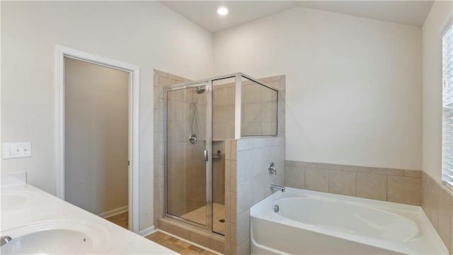 full bathroom featuring double vanity, a garden tub, vaulted ceiling, a shower stall, and a sink