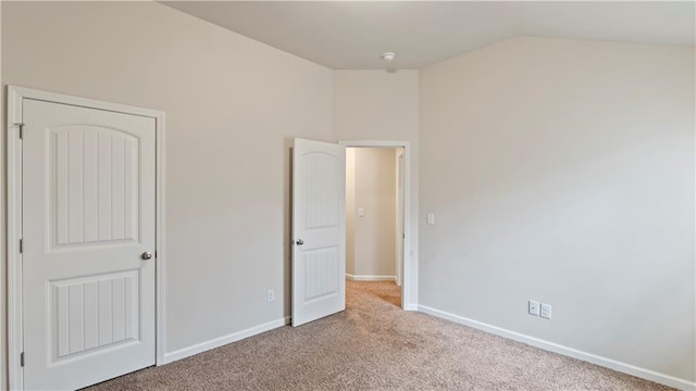 unfurnished bedroom featuring lofted ceiling, carpet, and baseboards