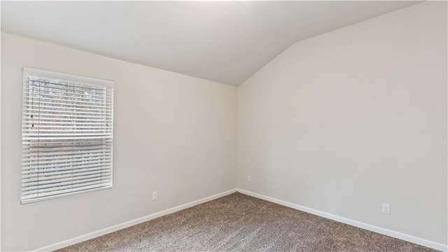 empty room featuring carpet floors, lofted ceiling, and baseboards