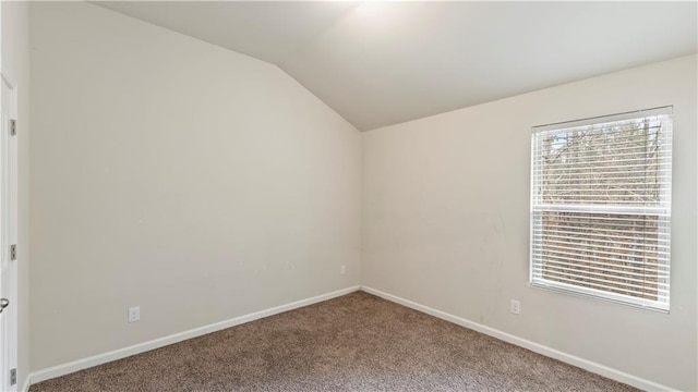 spare room featuring carpet floors, baseboards, and vaulted ceiling