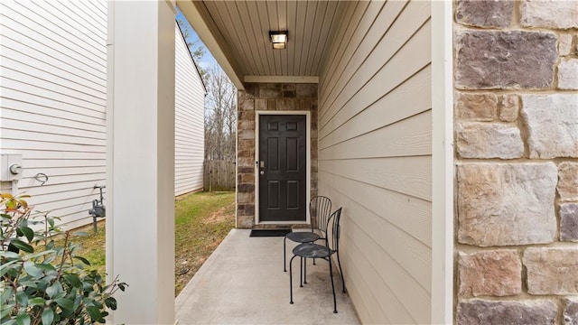 property entrance featuring stone siding and fence