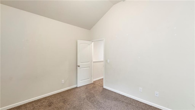 empty room with carpet floors, lofted ceiling, and baseboards