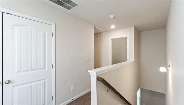 corridor with an upstairs landing, baseboards, visible vents, carpet, and attic access