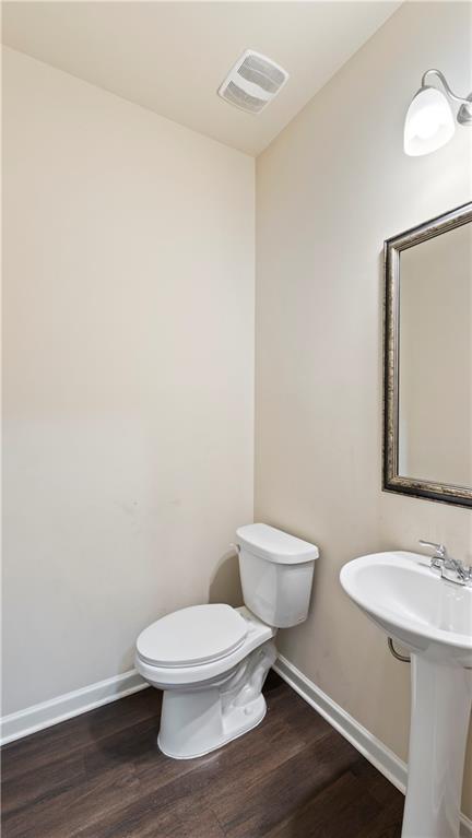 bathroom featuring visible vents, toilet, baseboards, and wood finished floors