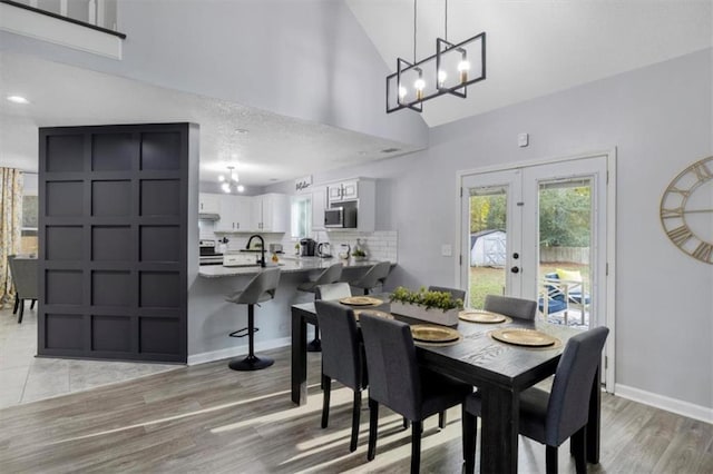 dining area featuring high vaulted ceiling, french doors, light wood-style flooring, and baseboards