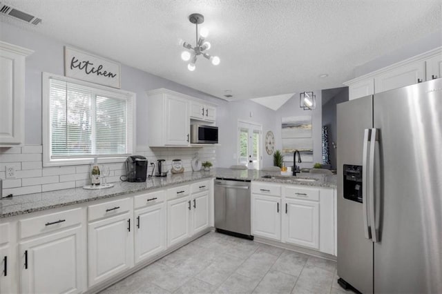 kitchen with visible vents, backsplash, appliances with stainless steel finishes, white cabinets, and a sink