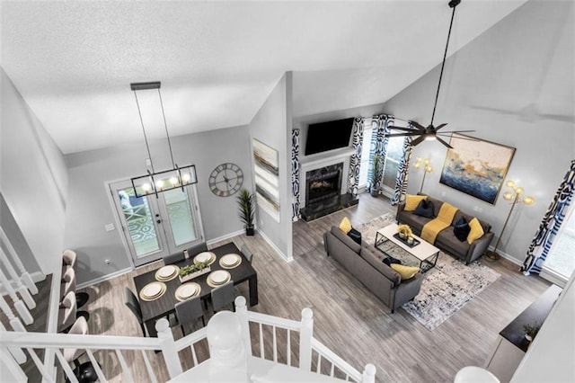 living room featuring a premium fireplace, baseboards, wood finished floors, and ceiling fan with notable chandelier