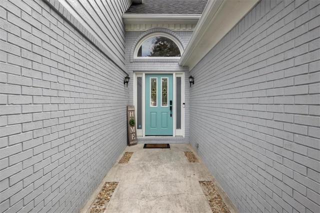 view of exterior entry with roof with shingles