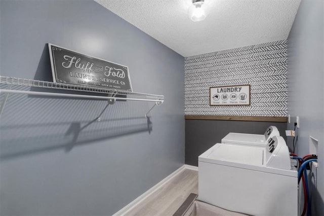 laundry area featuring laundry area, baseboards, washer and clothes dryer, wood finished floors, and a textured ceiling