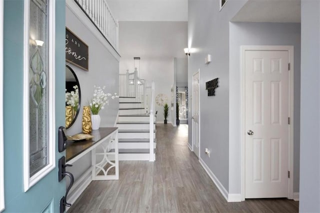 entrance foyer with baseboards, stairway, and wood finished floors