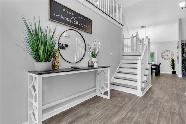 foyer with a high ceiling, stairs, baseboards, and wood finished floors