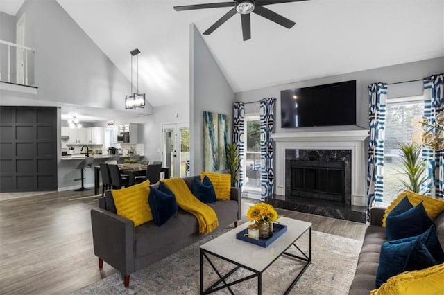 living area with a premium fireplace, a ceiling fan, vaulted ceiling, and wood finished floors