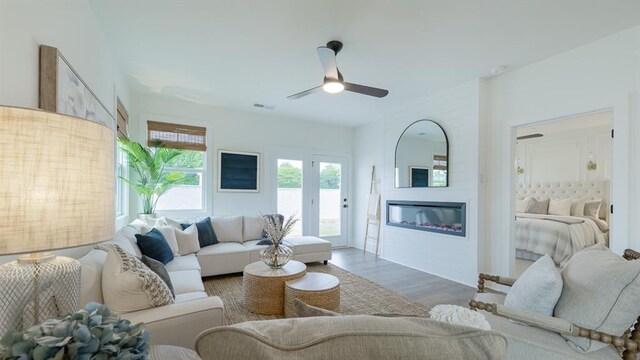 living room featuring a ceiling fan, wood finished floors, and a glass covered fireplace