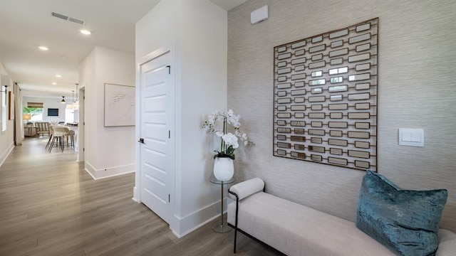 hallway with wood finished floors, baseboards, recessed lighting, an accent wall, and wallpapered walls
