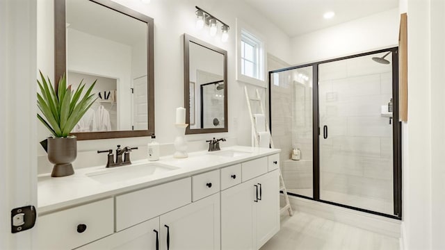 bathroom with a stall shower, double vanity, and a walk in closet