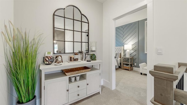 hallway featuring light colored carpet and baseboards