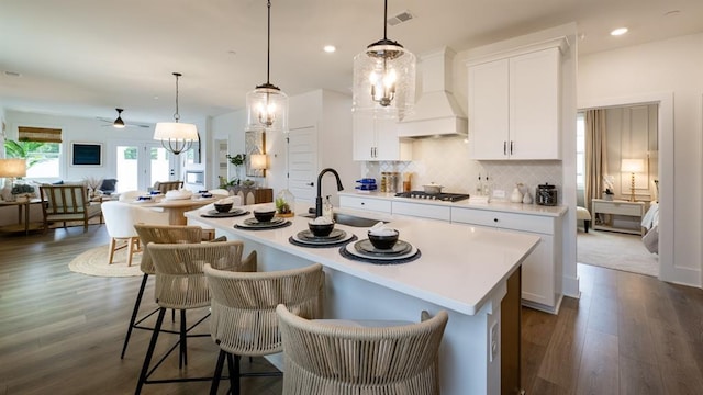 kitchen featuring premium range hood, a sink, stainless steel gas stovetop, ceiling fan, and a kitchen island with sink