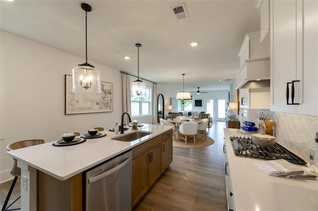 kitchen with stainless steel dishwasher, a sink, open floor plan, dark wood finished floors, and recessed lighting