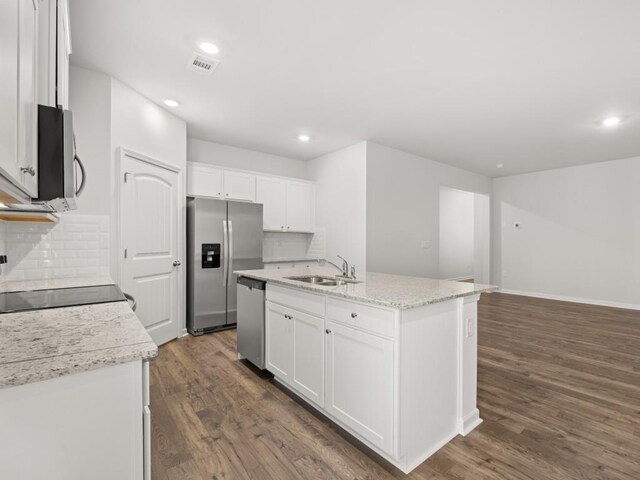 kitchen featuring dishwasher, an island with sink, open floor plan, wood finished floors, and a sink