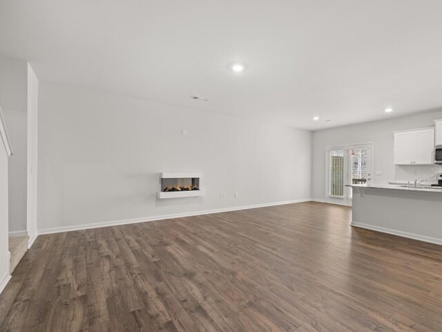 living area with dark wood-type flooring, stairway, recessed lighting, and baseboards