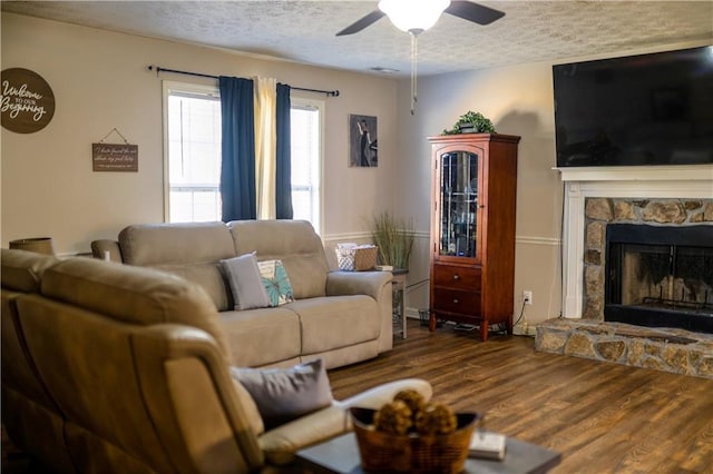 living room with hardwood / wood-style flooring, ceiling fan, a fireplace, and a textured ceiling