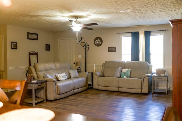 living room featuring ceiling fan, dark wood-type flooring, and a textured ceiling