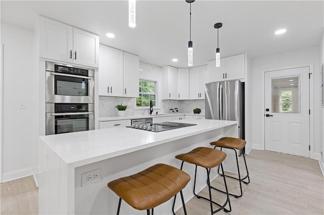 3614 N Druid Hills Rd N, Decatur, GA 30033 - kitchen with appliances with stainless steel finishes, a kitchen breakfast bar, white cabinetry, light wood-type flooring, and recessed lighting