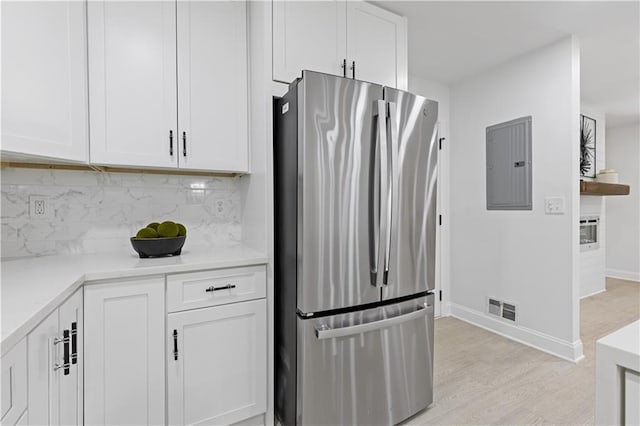 3614 N Druid Hills Rd N, Decatur, GA 30033 - kitchen with freestanding refrigerator, electric panel, light wood-type flooring, decorative backsplash, and white cabinets