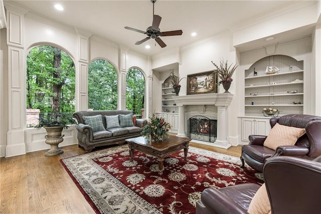 8970 Moor Park Run, Duluth, GA 30097 - living area featuring built in features, ceiling fan, crown molding, wood finished floors, and a lit fireplace