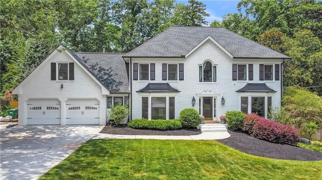 colonial-style house with a garage, driveway, brick siding, and a front yard