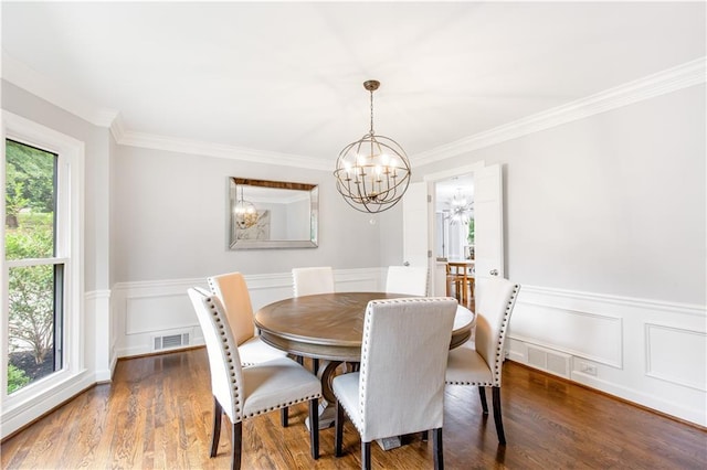 dining area featuring a notable chandelier, dark wood-style flooring, visible vents, ornamental molding, and wainscoting