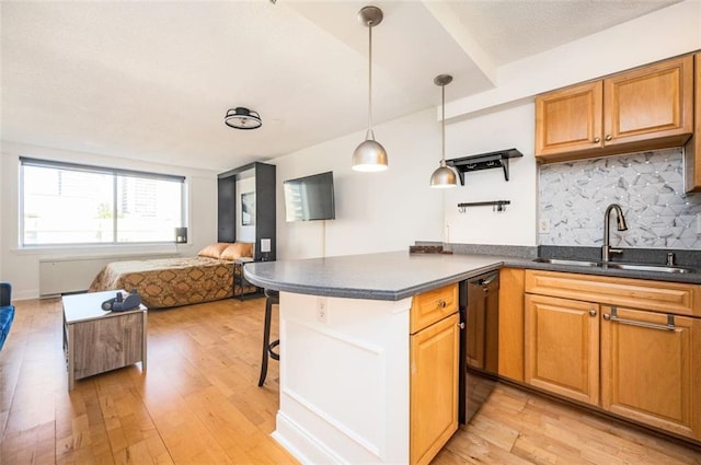 kitchen featuring decorative backsplash, a breakfast bar, light hardwood / wood-style flooring, decorative light fixtures, and sink