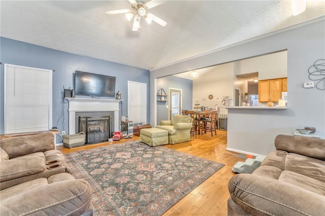 living room with ceiling fan, light hardwood / wood-style floors, and lofted ceiling