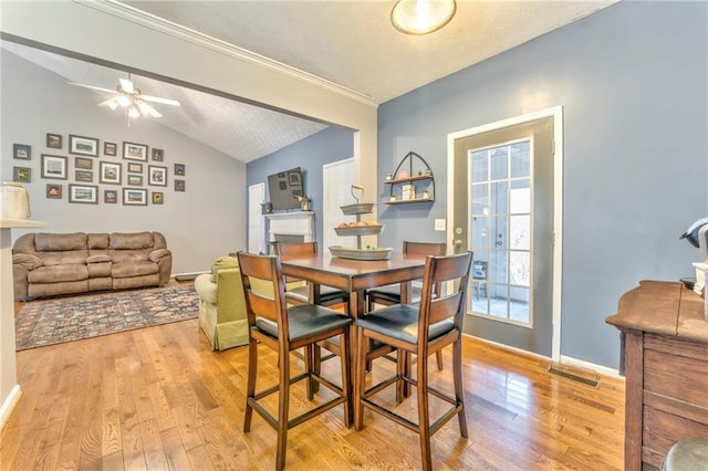 dining room with ceiling fan, light hardwood / wood-style floors, a textured ceiling, and lofted ceiling