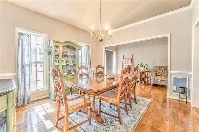 dining room featuring a chandelier, light hardwood / wood-style flooring, and crown molding