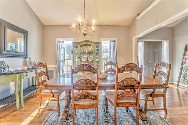 dining area with vaulted ceiling, light hardwood / wood-style flooring, a notable chandelier, and a healthy amount of sunlight