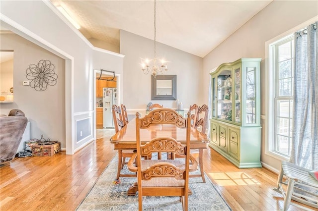 dining area with light wood-type flooring, an inviting chandelier, and plenty of natural light