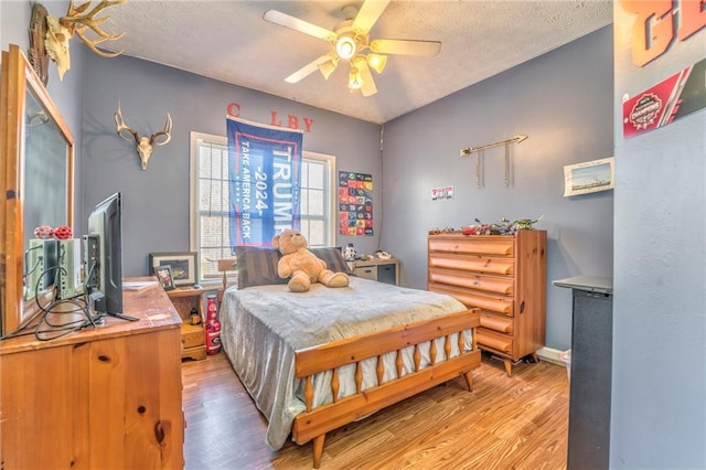 bedroom featuring ceiling fan, light hardwood / wood-style flooring, and a textured ceiling