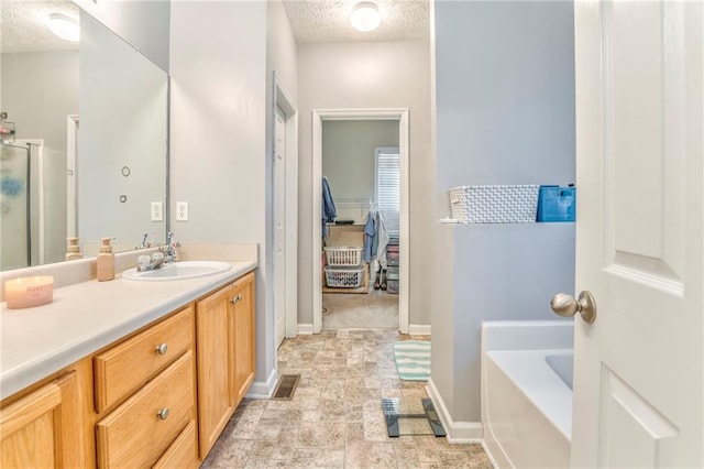 bathroom with independent shower and bath, a textured ceiling, and vanity