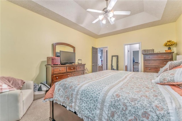 carpeted bedroom with ceiling fan and a raised ceiling