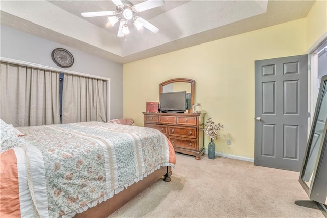 carpeted bedroom featuring ceiling fan and a raised ceiling