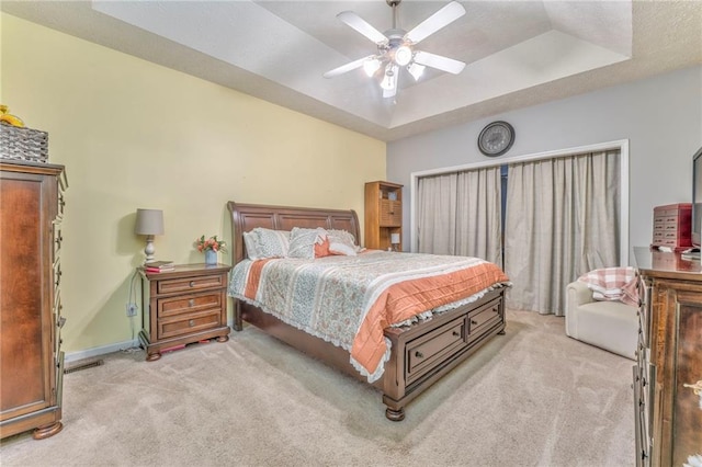 carpeted bedroom featuring ceiling fan and a tray ceiling