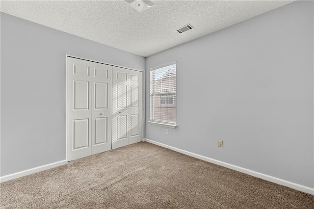 unfurnished bedroom featuring a textured ceiling, a closet, and carpet