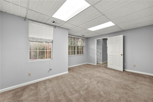 empty room with a healthy amount of sunlight, a paneled ceiling, and carpet flooring