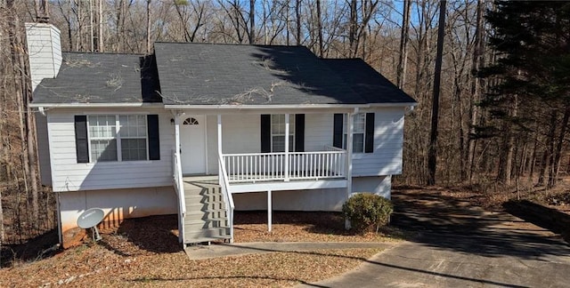 view of front of house featuring covered porch, a chimney, and stairs