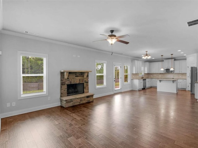149 Elkins Blvd, Locust Grove, GA 30248 - unfurnished living room featuring a ceiling fan, plenty of natural light, ornamental molding, a stone fireplace, and dark wood-style floors