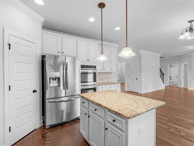 149 Elkins Blvd, Locust Grove, GA 30248 - kitchen with appliances with stainless steel finishes, a kitchen island, white cabinetry, dark wood-style flooring, and ornamental molding