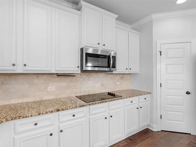 149 Elkins Blvd, Locust Grove, GA 30248 - kitchen featuring stainless steel microwave, black electric stovetop, white cabinets, light stone countertops, and tasteful backsplash