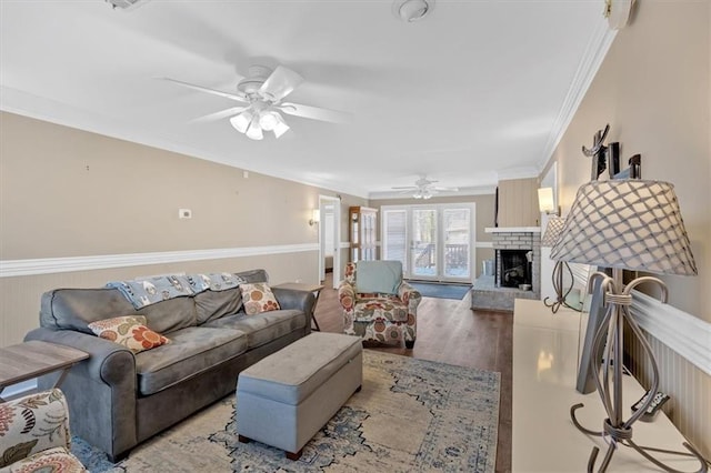 living room featuring a fireplace, ornamental molding, light hardwood / wood-style floors, and ceiling fan